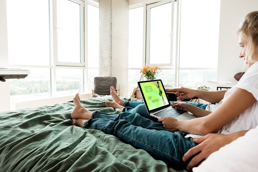 Person with a laptop on a bed, shopping online