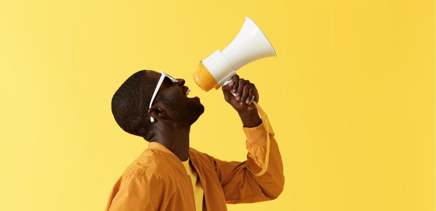 Man shouting into a megaphone against a yellow background